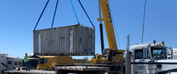 Shipping container being lifted by crane onto a trailer